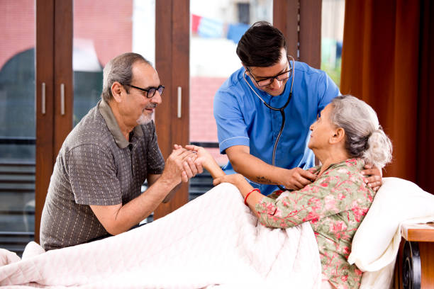 home caregiver examining senior woman using stethoscope on bed